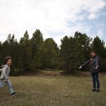 Mother and child enjoying playtime in lush Swiss landscape with trees.